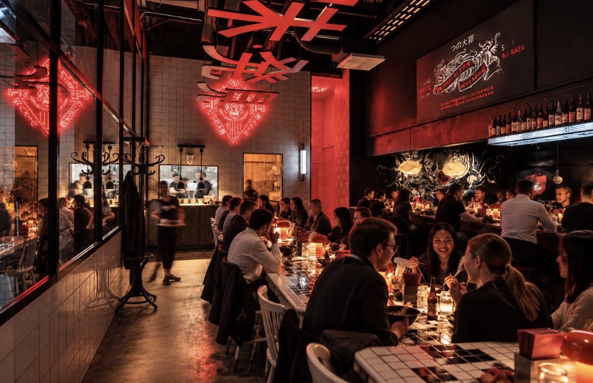 Restaurang med röda neonskyltar, kakelbord och öppet kök