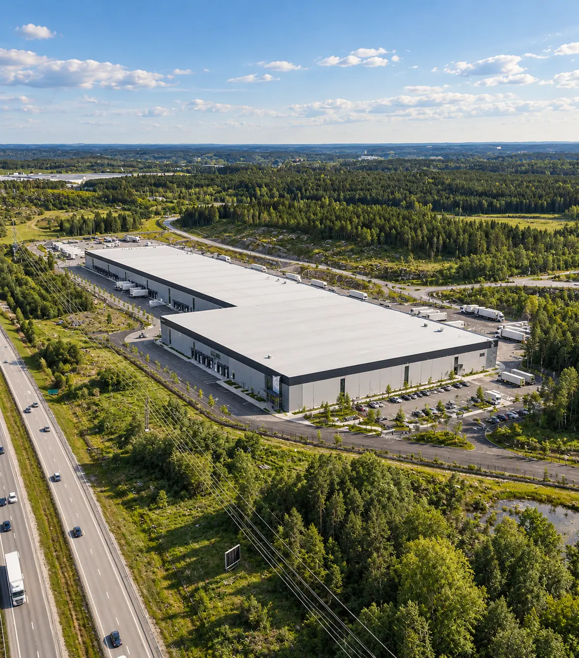 Flygfoto över logistikcenter med lastkajer, uppställningsytor för lastbilar och omgivande skog