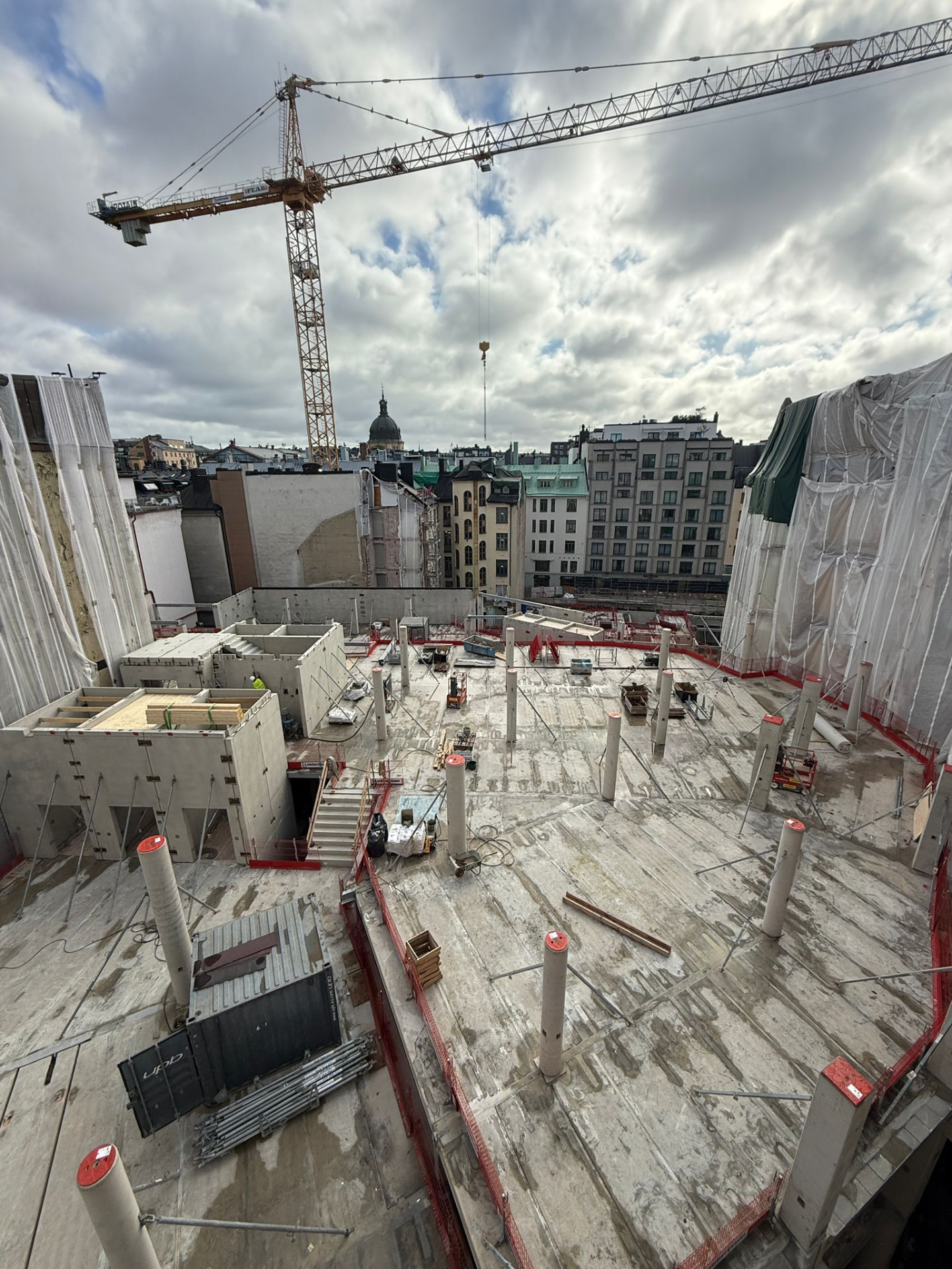 Betongdäck på byggplats med tornkran, sedd över stadsbebyggelse