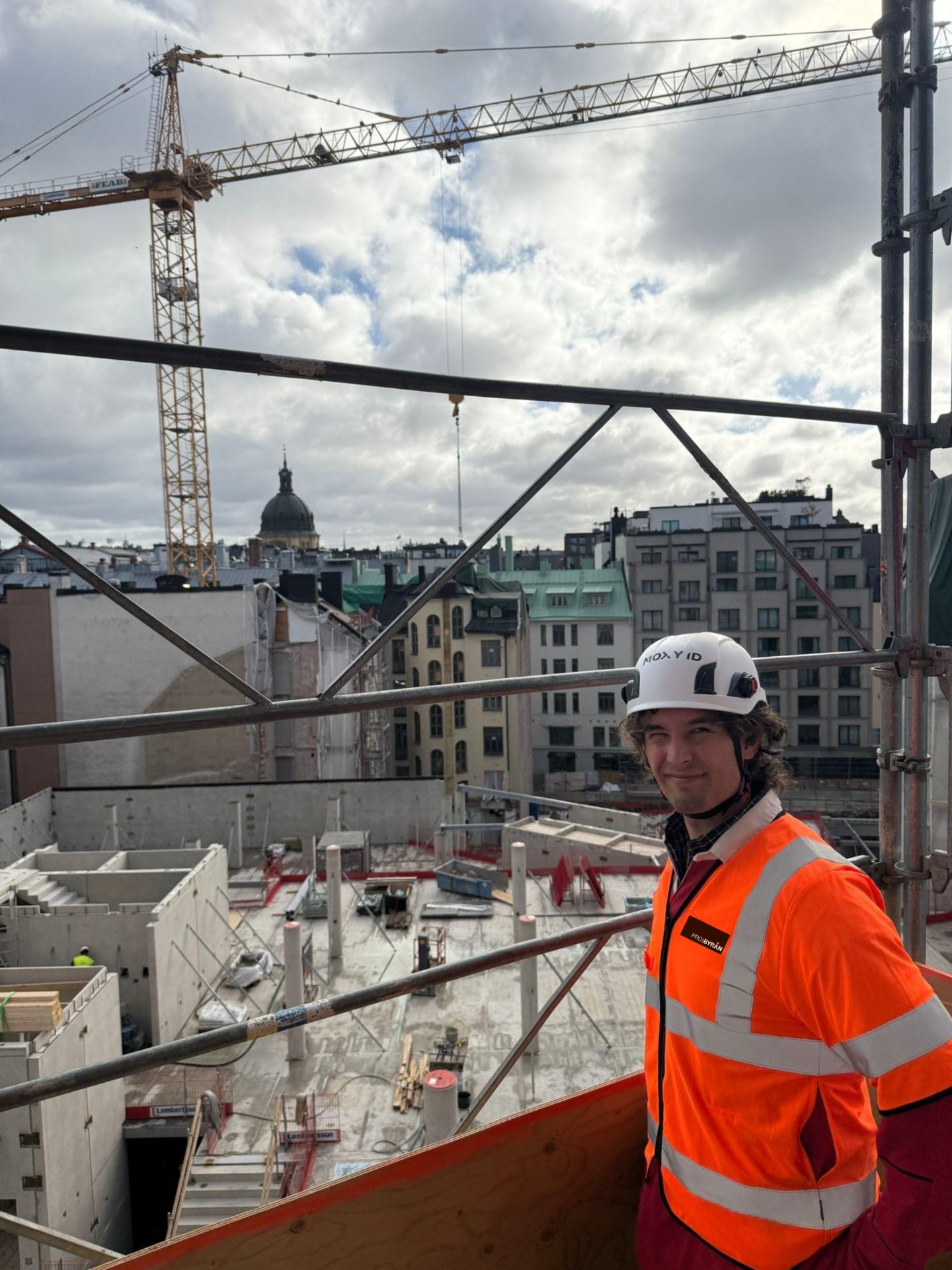 Kollega i varseljacka och hjälm på ställning på en byggplats